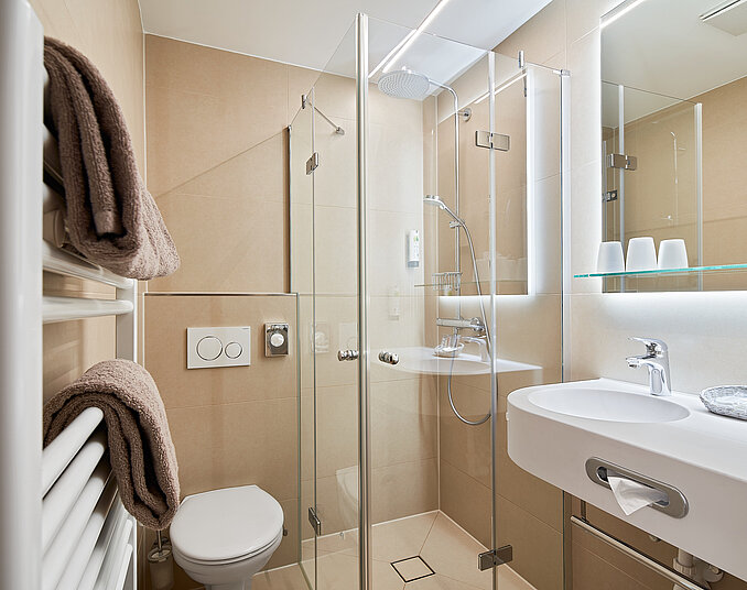 Modernes Bad mit Glasdusche und Handtüchern – komfortable Ausstattung der Hotelzimmer am Bodensee.