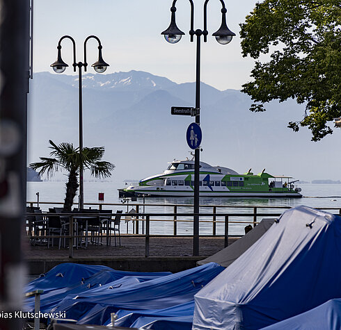 Katamaran auf dem Bodensee mit Blick auf die Alpen und Promenade in Friedrichshafen.