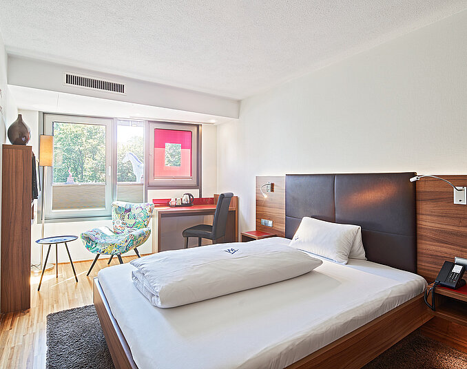 Helles Einzelzimmer mit Schreibtisch und Balkon – moderne Hotelzimmer am Bodensee erleben.