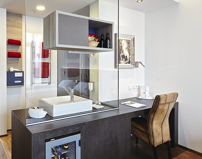 Modernes Hotelzimmer mit offenem Badezimmer, stilvollem Waschtisch, Schreibtisch und Minibar.
