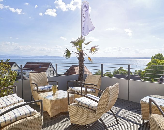 Sonnenterrasse mit Seeblick und Palmen – entspannter Genuss für Wellness in Friedrichshafen.