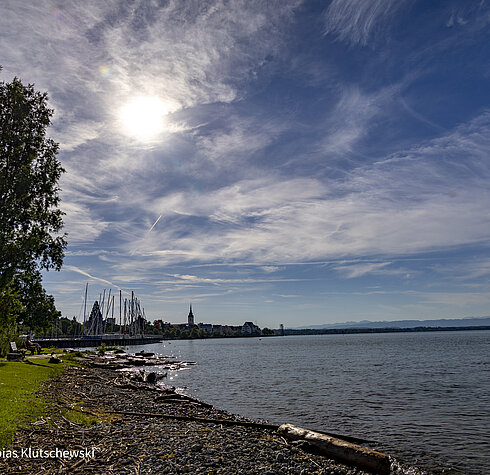 Uferpromenade und Yachthafen Friedrichshafen am Bodensee Ufer des Bodensees mit Blick auf den Yachthafen und die Skyline von Friedrichshafen unter einem sonnigen Himmel.