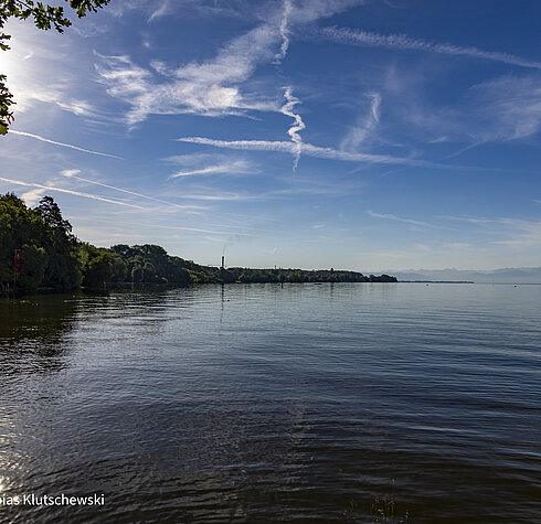Blick über den Bodensee an einem sonnigen Tag mit blauem Himmel und vereinzelten Wolkenformationen.